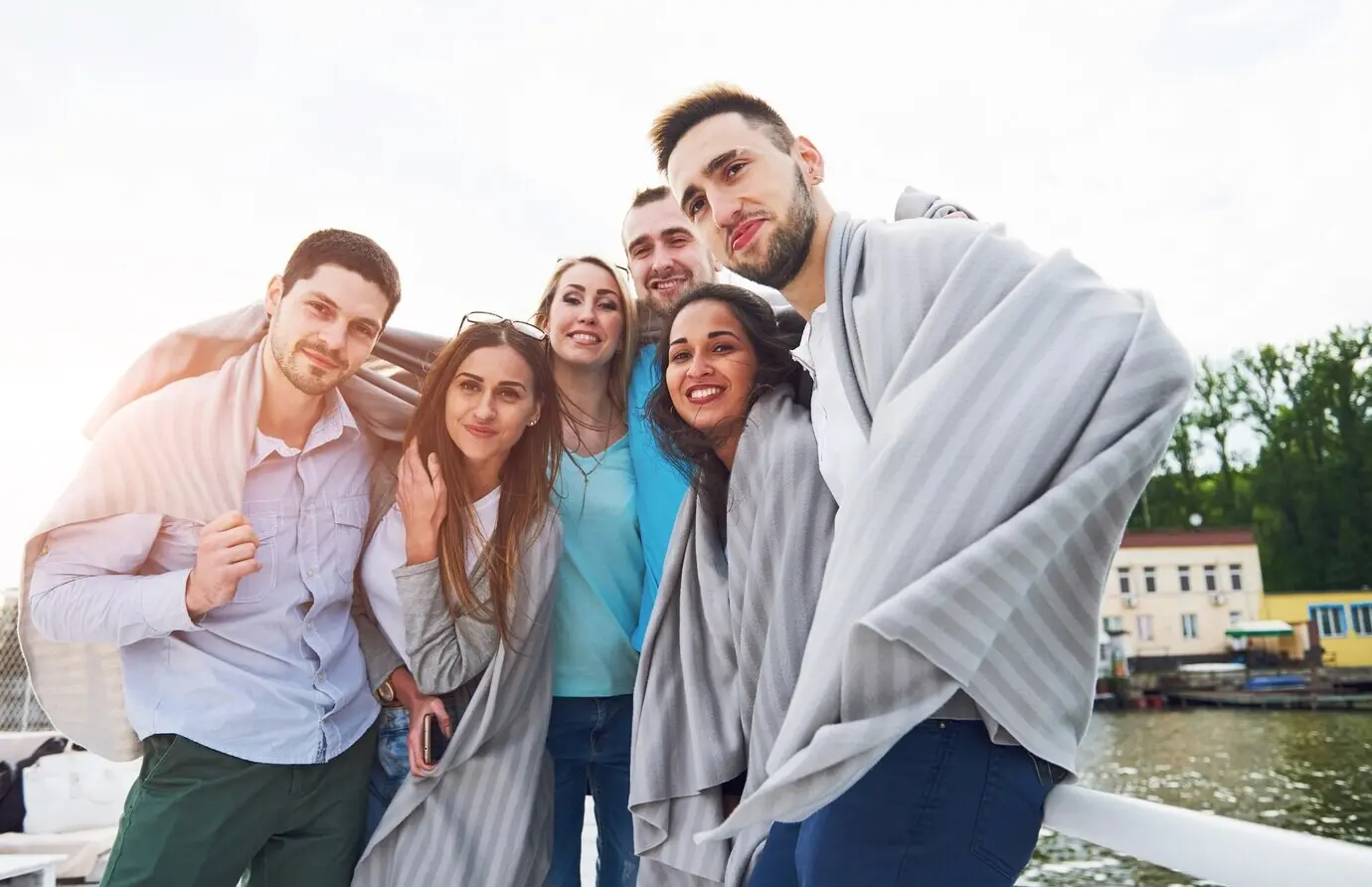 Lächelnde, glückliche Gruppe von Freunden im Freien auf der Seebrücke am Strand.